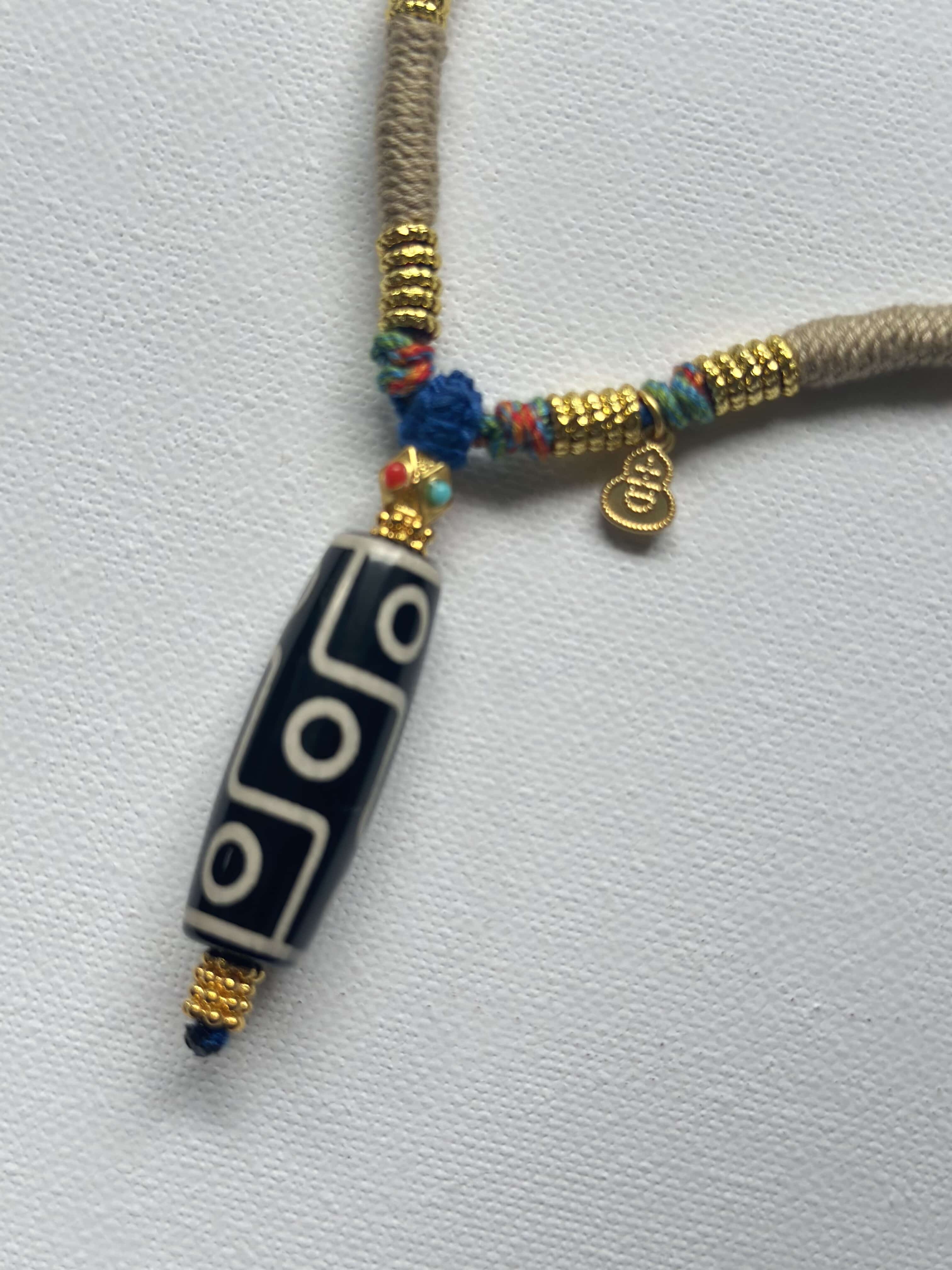 Heavily handwoven necklace with Gold plated metal lucky accessories and Vintage Nine-Eyed DZI bead pendant.